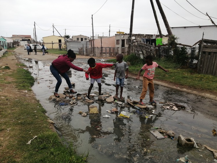 Children cross a stream of sewage in Soweto-on-Sea, Port Elizabeth.