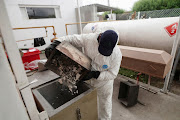 A crematorium employee empties a container with cremated bones and ashes from the body of a person who died of the coronavirus disease (Covid-19), at Parque Cementerio Zipaquira, in Zipaquira, Colombia June 3, 2021.