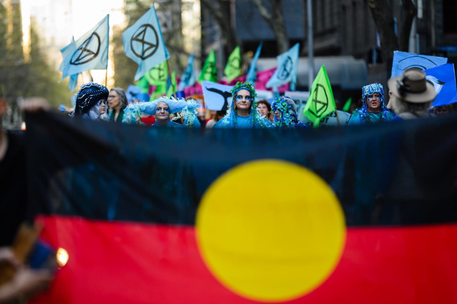 Rebels in blue costumes march with an indigenous flag