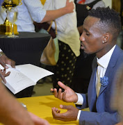 eko Modise sign his book during the Launch of the book, The Curse of Teko Modise at Exclusive Books, Mall of Rosebank on November 29, 2017 in Johannesburg.