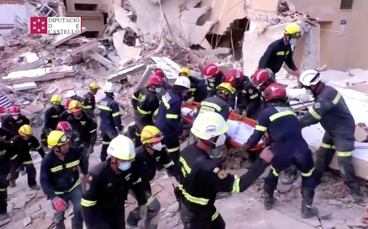 Firefighters carry a body on a stretcher among the debris of a collapsed building in the town of Peniscola, Spain, August 26, 2021.