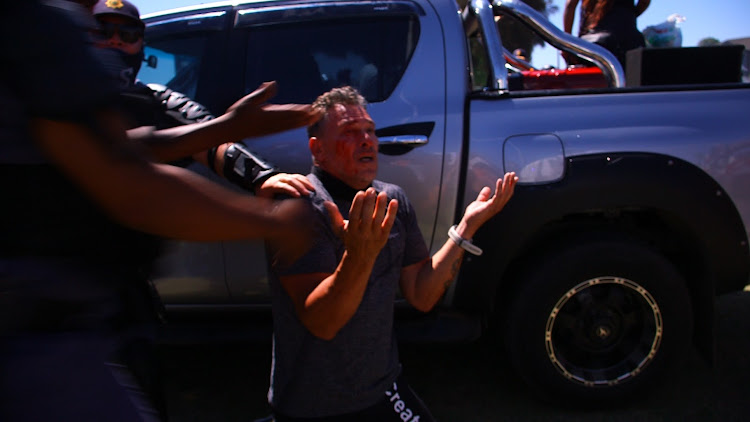 Public order police rescued the man who was set on by EFF protesters after he tried to interrupt party secretary-general Marshall Dlamini outside Brackenfell High School in Cape Town on November 20 2020.