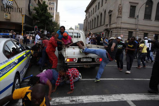 UNCIVIL DISOBEDIENCE: The ANC issued a statement late yesterday promising to ‘hastily discipline’ its Inner City branch secretary Thabiso Setona, filmed brutally assaulting women outside Luthuli House. He kicked a woman already lying down, and here is still trying to kick her as friends try to remove her onto the bakkie Picture: ALON SKUY