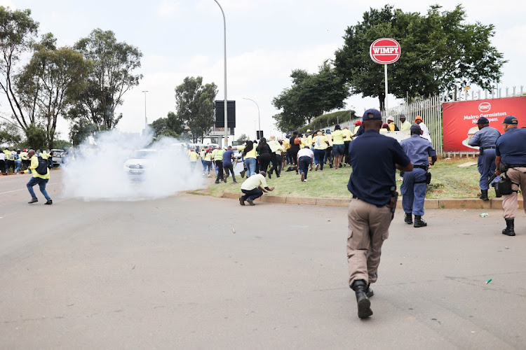 Police disperse striking Makro workers with rubber bullets and stun grenades outside Makro Germiston on Friday.