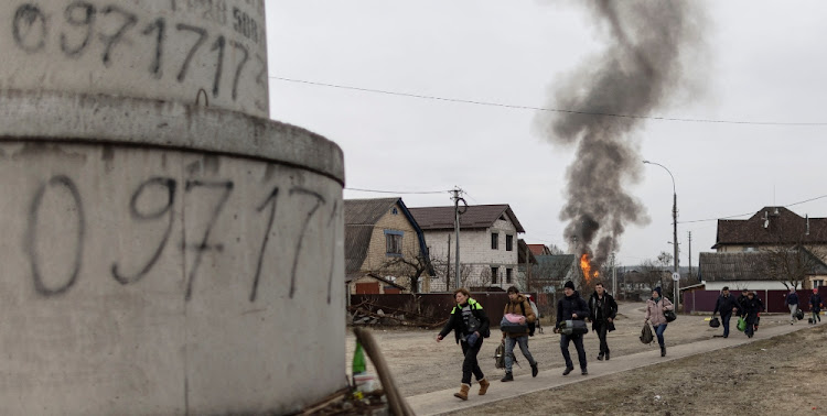 Local residents look for cover as they escape from the town of Irpin, after heavy shelling on the only escape route used by locals, while Russian troops advance towards the capital of Kyiv, in Irpin, near Kyiv, Ukraine on March 6 2022.