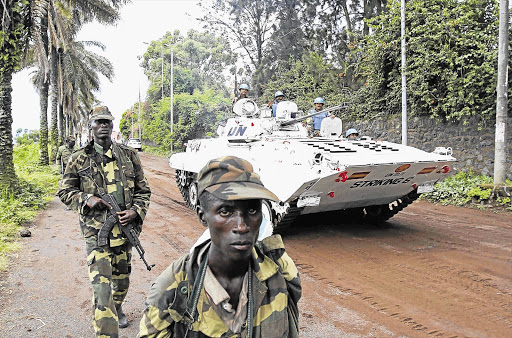 A UN peacekeepers' armoured vehicle drives past rebels patrolling a street in Goma, in the eastern Democratic Republic of Congo, soon after capturing the city from the government army.