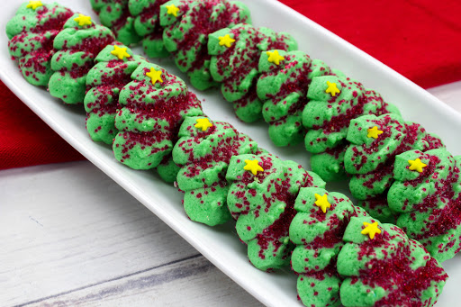 A plate of decorated Christmas tree spritz cookies.