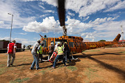 A  group of Winterveld community members help offload food from a helicopter flown by members of the Covid Flight team that donates supplies to disadvantaged communities during lockdown.