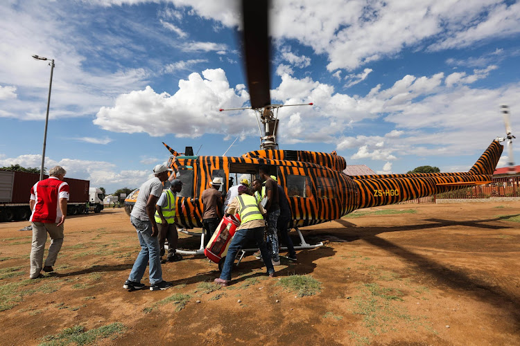 A group of Winterveld community members help offload food from a helicopter flown by members of the Covid Flight team that donates supplies to disadvantaged communities during lockdown.