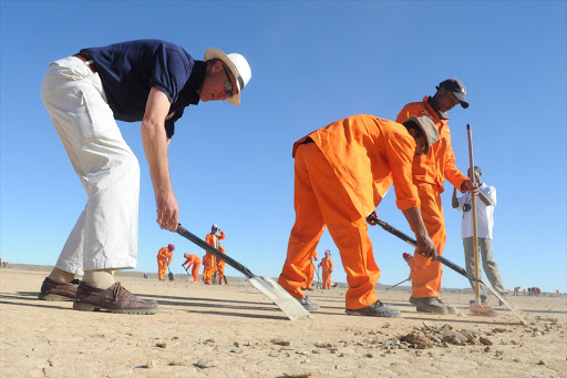 British Royal Air Force Wing Commander Andy Green and current holder of the World Land Speed Record helps clear stones from Hakskeen Pan, 200km from Upington on July 24, 2012 in the Northern Cape, South Africa. Green will lead the Bloodhound SSC team in their attempt to break the land speed record. A team of 300 previously unemployed people funded by the Northern Cape government cleared stones from the 10 million square metres of desert race track to prepare for the 2014 attempt. (