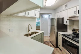 Modern apartment kitchen with stainless steel appliances, white cabinetry, and subway tile backsplash.