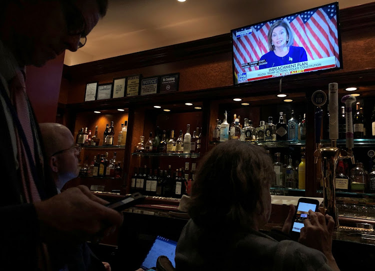 Members of the White House press corps - holding in the Trump Bar at Trump Tower - watch U.S. House Speaker Nancy Pelosi (D-CA) live on television as she announces an impeachment investigation of U.S. President Donald Trump on September 24, 2019.