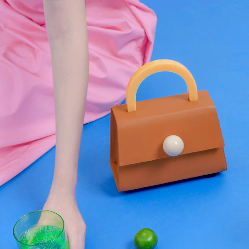 Bolsa de mão, ombro e mensageiro com design de bola e cores combinadas em acrílico, ideal para looks diversos, leve e moderna.