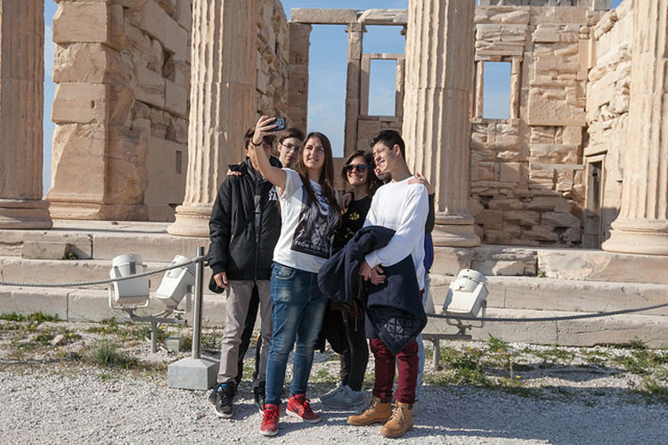 Millennial travelers pose for a selfie in front of the Erechtheion in Athens.