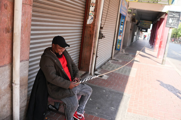 Security guard Gudda Ngubane sits with a sjambok in the Johannesburg CBD.