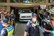 Members of the media waiting for a sighting of Serbian tennis player Novak Djokovic surround a departing transport vehicle exiting the Park Hotel, where the athlete has been held during a legal challenge over his visa, in Melbourne, Australia, on January 10 2022.