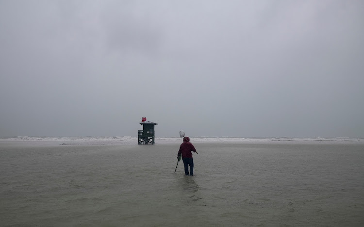 A person uses a metal detector on the beach engulfed by water before the arrival of Tropical Storm Eta in Siesta Key, Florida, US November 11, 2020.