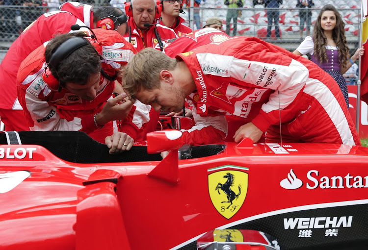 Ferrari Formula One driver Sebastian Vettel of Germany looks into his car during a past race