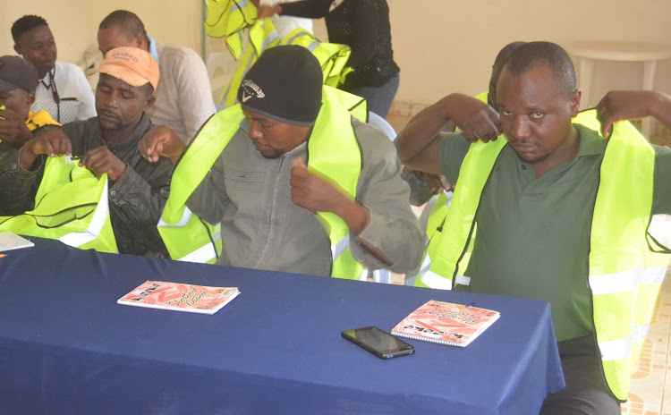 Boda boda leaders from Kitui West sub county putting on reflectors donated to them by the county government of Kitui during the Monday meeting.