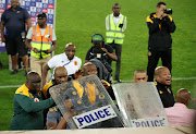 Kaizer Chiefs coach Ntseki Molefi is escorted by police, protecting him with riot shields, as fans throw missiles at him after his team's 1-0 DStv Premiership defeat against SuperSport United at Peter Mokaba Stadium in Polokwane on Wednesday night.