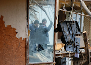 Workers are reflected in a mirror while removing debris of a residential building heavily damaged in recent shelling in the Ukraine's Donetsk region.