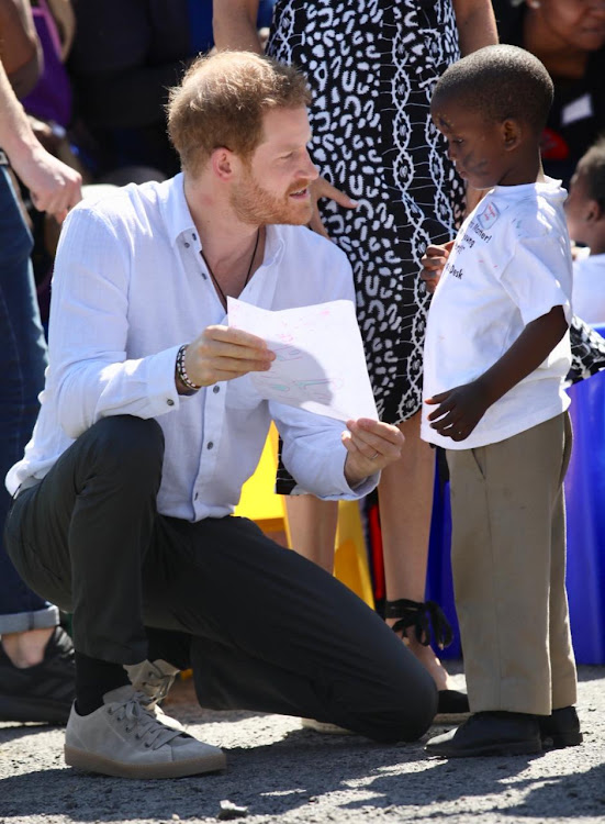 Prince Harry chats to a young boy about a picture he drew during the royal's visit to Nyanga in Cape Town.