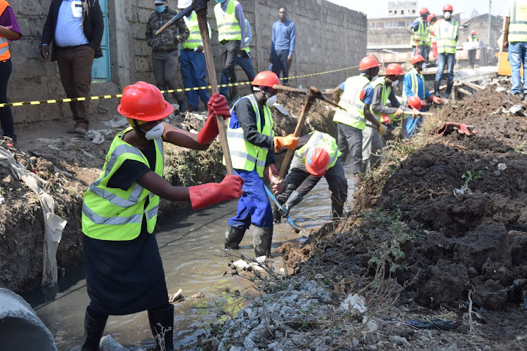 Workers at Chuma Mbili, Githurai, clear the stormwater drainage in readiness for concrete works