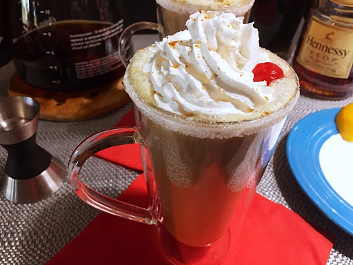 A coffee topped with whipped cream and cherry.