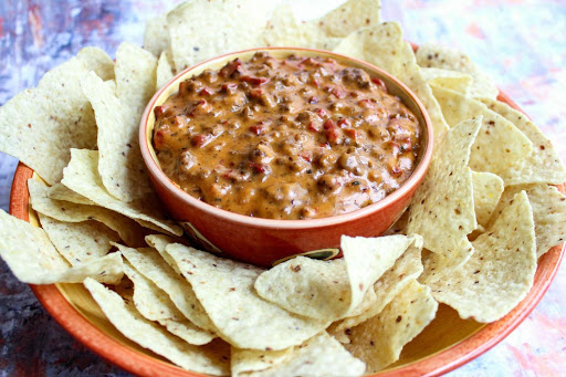 Pizza dip in an orange bowl with tortilla chips around the bowl.