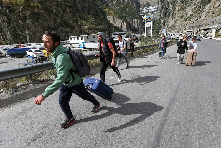 Travellers walk after crossing the border with Russia at the frontier checkpoint in Georgia, September 28 2022. Picture: IRAKLI GEDENIDZE/ REUTERS