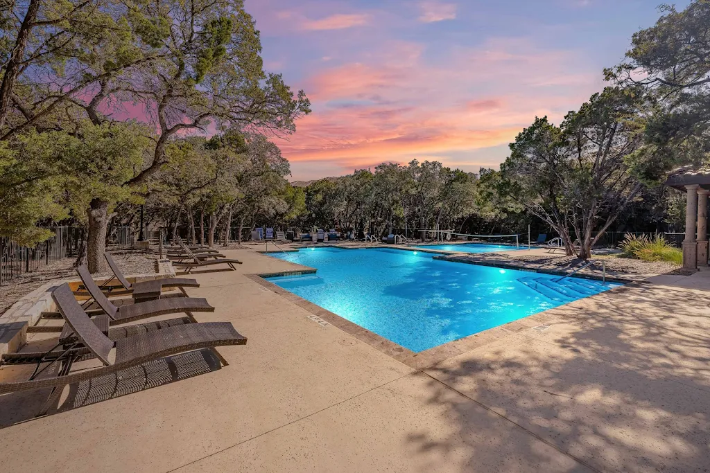 Bridge at Heritage Woods' swimming pool at dusk with large sundeck featuring brown lounge chairs