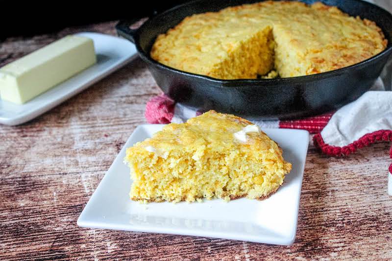 A Slice Of Southern Cornbread With Butter On A Plate.