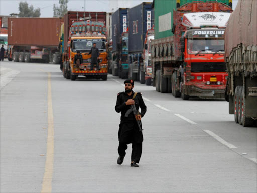 A policeman walks in front of supply trucks carrying containers, after the opening of Pakistan Afghan Torkham border, in Landi Kotal, Pakistan March 21, 2017. /REUTERS