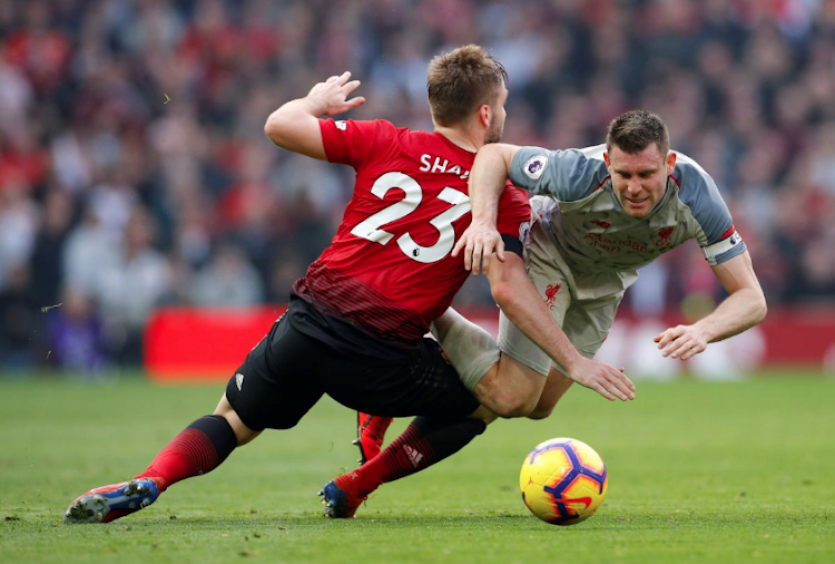 Liverpool's James Milner tumbles after a challenge by Manchester United defender Luke Shaw