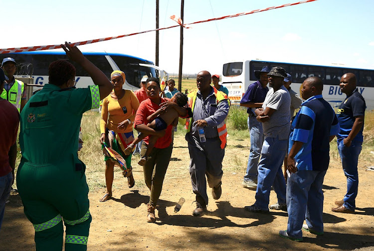 A small child is taken from one of at least six buses brought in to transport passengers to an ambulance — apparently a victim of heatstroke.