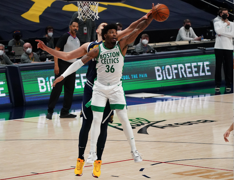 Boston Celtics' guard Marcus Smart grabs a rebound away from Denver Nuggets center Nikola Jokic