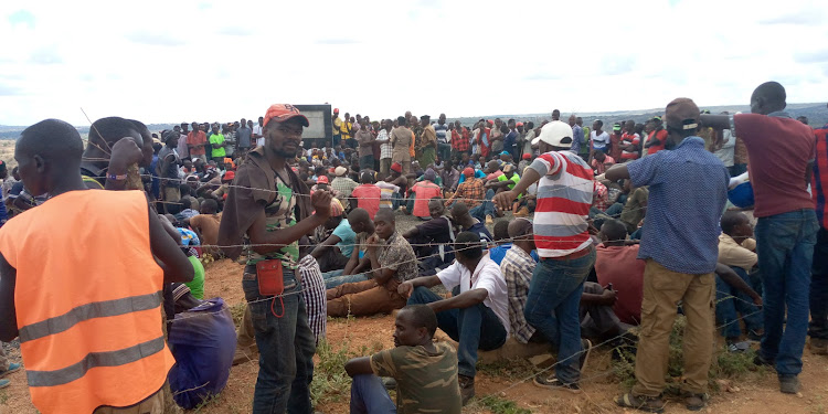 Workers assemble at Thwake dam site gate on Friday. They want higher wages and better terms of engagement.