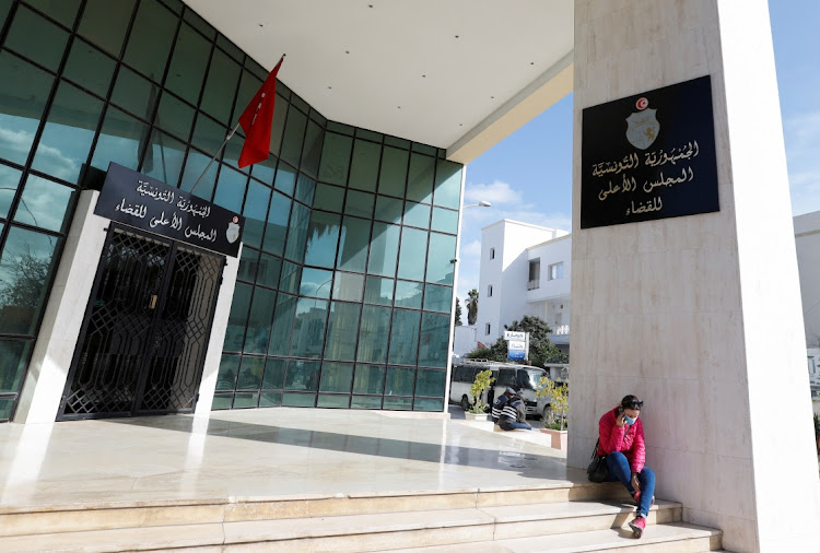 A woman sits outside the Supreme Judicial Council building in Tunis, Tunisia February 6, 2022.