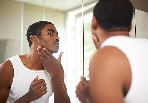 A black man checking his stubble in mirror