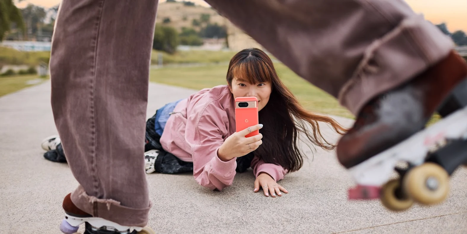 A person uses their Pixel 8 in Coral color to take a video of their rollerskating friend.