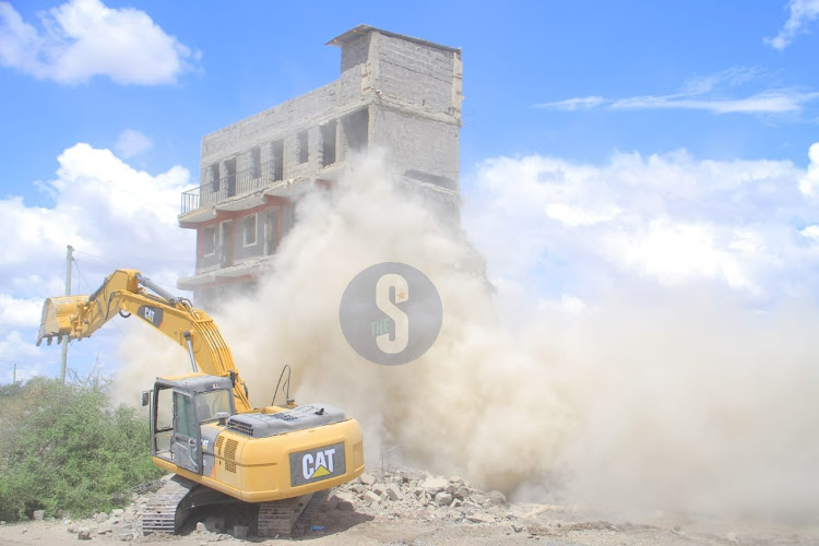 A bulldozer brings down a building on the disputed Portland land in Athi River on October 15, 2023.