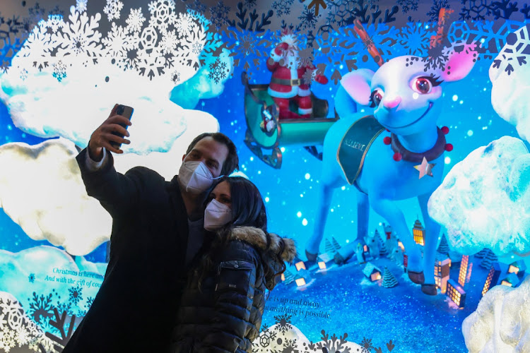 People in face masks take a selfie in front of the Macy's Holiday Windows as the Omicron coronavirus variant continues to spread, in Manhattan, New York City, U.S., December 18, 2021.