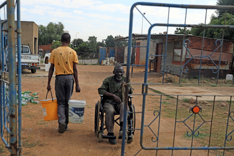 One of the residents of Hammanskraal helps Isaac Masango on a wheel chair to get water that is delivered to their area by tankers