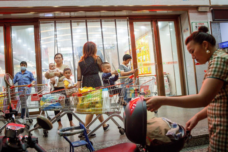 A woman holds a baby outside a supermarket in Qinzhou, Guangxi province, China, on April 12 2021. The birth rate in China has continued to decline.