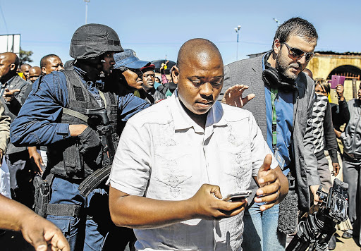 Journalist Nickolaus Bauer, right, pleads as a member of the presidential VIP security detail deletes Bauer's pictures of police carrying ANC T-shirts intended for handing out.