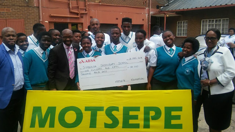 Gavin Mofokeng (in brown suite), is the principal of Siyabonga Secondary in Braamfischerville, Soweto. He stands with a cheque of R150,000 from the Motsepe Foundation which the school received at the event in Regina Mondi Church, Soweto.