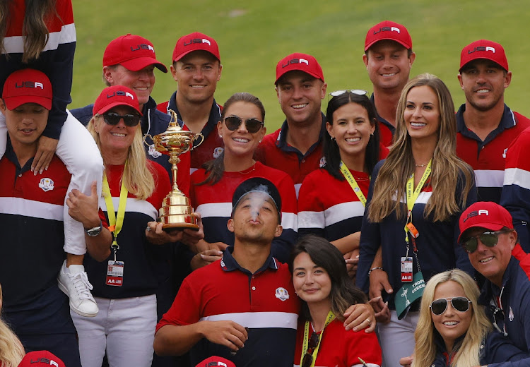 Team US and their partners pose with the trophy after winning the Ryder Cup