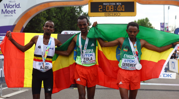 Ethiopia's Tamirat Tola celebrates winning the men's marathon alongside silver medallist Mosinet Geremew and bronze medallist Bashir Abdi.