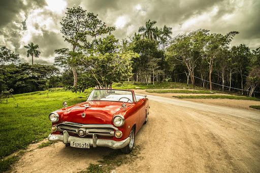 A vintage car parked on a dirt road in Cuba.