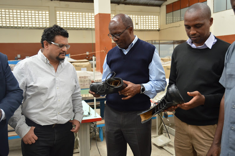 Chairman of the Tanners Association of Kenya and director of Reddamac Lether Center Robert Njoka (center together with the association treasurer Anut Parmar and Board member Douglas Mokua show some of the military boot made at Reddamac factory yesterday. The association has asked the government to assist in developing the leather production to international standard through providing experienced field officers and reviewing tax added on leather imports.